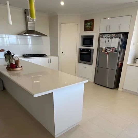 A Perth home kitchen with its stone island and benchtops wiped down after a clean